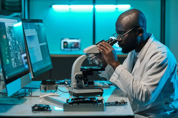 Fiatal komoly férfi kutató fehérköpenyben keres mikroszkóp — Stock Fotó