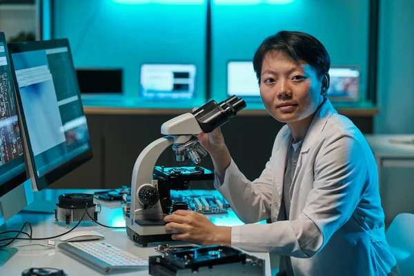 Young Asian researcher in whitecoat working with microscope — Stockfoto