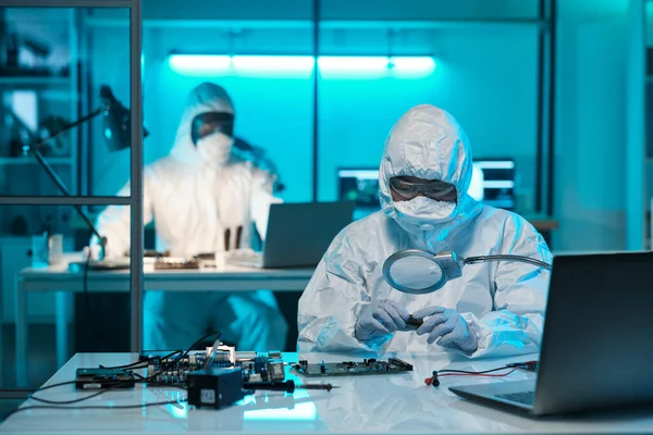 Young female scientist in protective workwear looking at microchip — Fotografia de Stock