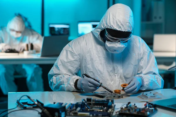 Hedendaagse technicus in beschermende werkkleding solderen kleine onderdelen van printplaat — Stockfoto