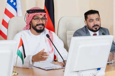 Genç kendinden emin Arap delege konferansta mikrofonda konuşuyor