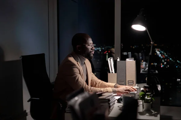 Busy young African man typing on computer keyboard — 图库照片