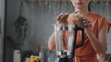 El kamerasıyla, mutfakta smoothie yaparken karabuğday bala buğday koyan genç bir kadının izini sürüyorum.