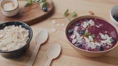 Mutfak masasında nefis böğürtlenler, badem ve hindistan cevizi taneleri, nane ve meyve suyu kasesi var.