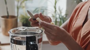 Blender 'da hindistancevizi parçalarını kesen ve ekleyen tanınmamış vejetaryen bir kadının el kamerası.