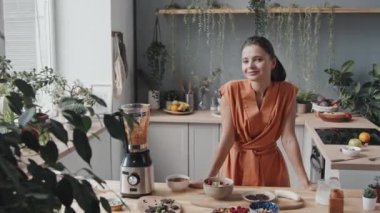 Kahvaltı için lezzetli meyve suyu kasesi yaptıktan sonra güzel vejetaryen bir kadının portresi.