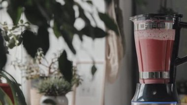 PAN yakın çekim pembe smoothie karıştırma ve karıştırma mutfak blender bir sürü bitki ile