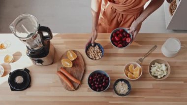 Tanınmayan genç bir kadının mutfağa girdiği ve sabahları smoothie yaparken lezzetli kirazları miksere koyduğu en iyi manzara.