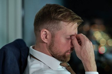 İş yerinde oturan yorgun genç işadamının yan görünüşü