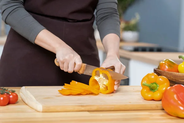 Hands of young female chopping fresh yellow capsicum — Stockfoto