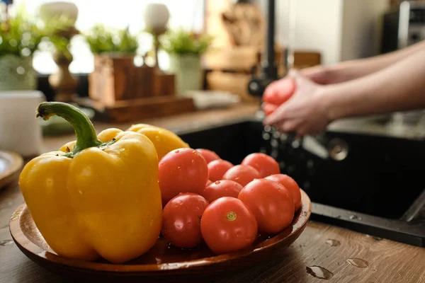 Свіжі та чисті стиглі помідори та жовтий паприка на дерев'яній тарілці — стокове фото