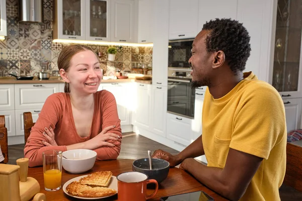 Счастливая молодая межкультурная пара болтает за завтраком — стоковое фото