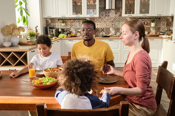 Молодая христианская семья из четырех человек молится перед ужином — стоковое фото