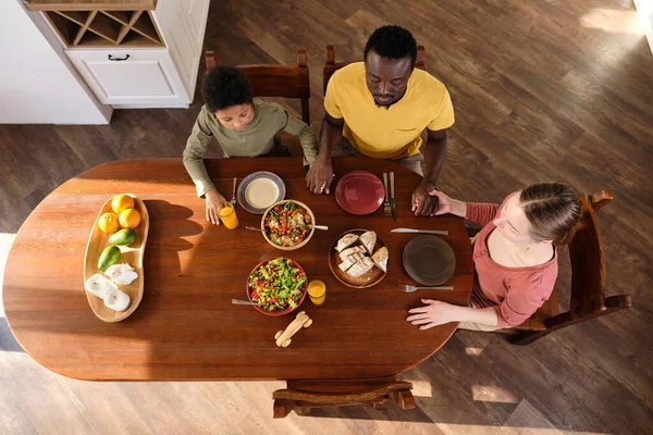 Contemporain jeune famille interracial priant avant de manger — Photo