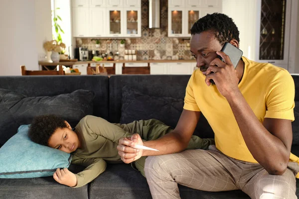Fiatal afrikai férfi okostelefonnal fül hívó orvos — Stock Fotó