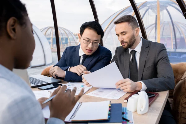 Two foreign business partners discussing terms of contract — Stockfoto