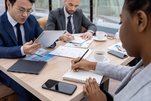 Joven empresaria africana apuntando a la página en blanco del cuaderno mientras planifica el trabajo —  Fotos de Stock