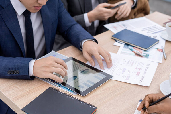 Contemporary economist in suit looking through charts and diagrams in tablet