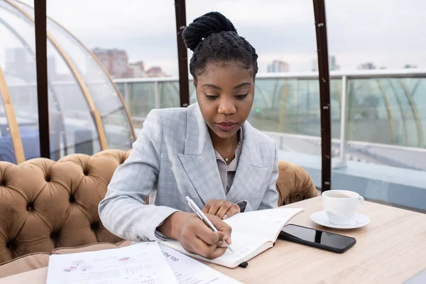Jeune femme d'affaires africaine élégante écrivant le plan de travail — Photo