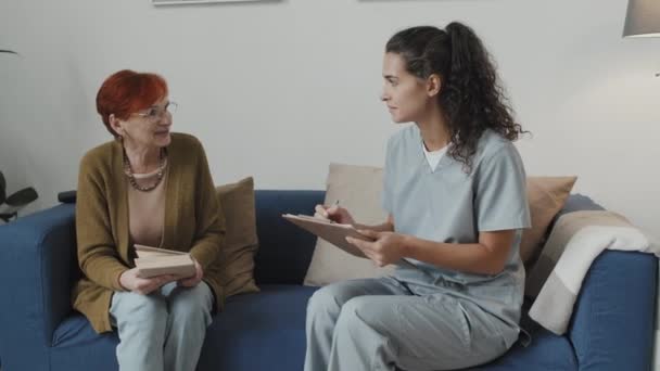 Medium Shot Young Nurse Taking Notes Clipboard While Talking Happy — Vídeo de Stock