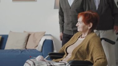 Tekerlekli sandalyedeki yaşlı kadının ve huzurevindeki diğer yaşlı insanların sıcaklığını ölçen ve onlara ilaç veren çok ırklı hemşirelerin fotoğraflarını çekiyorum.