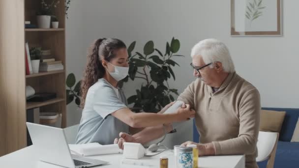 Medium Shot Young Female Doctor Face Mask Monitoring Blood Pressure — Vídeo de Stock