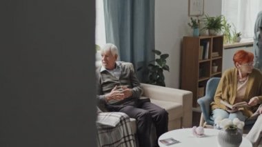 Huzurevinde oturma odasında televizyon başında oturup sohbet eden bir grup son sınıf öğrencisinin PAN görüntüsü.