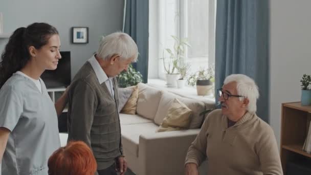 老人ホームでボードゲームをしている高齢者の陽気なグループの中で撮影挨拶新人と彼らの会社に彼を招待 — ストック動画