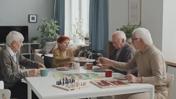 Средний Снимок Веселой Группы Пожилых Людей Сидящих Вокруг Стола Доме — стоковое видео