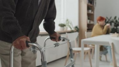 Huzurevinde Walker 'ın yardımıyla engelli yaşlı bir adamın orta bölüm fotoğrafı.