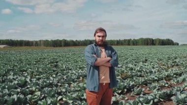 Kafkasyalı bir gencin lahana tarlasında kolları çaprazlanmış, günlük giysiler içinde dikilirken çekilmiş yatay portre görüntüleri.