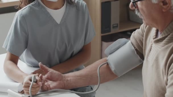 Handheld Medium Close Female Nurse Measuring Senior Man Blood Pressure — Stock Video