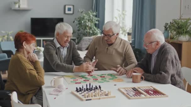 Střední záběr veselá skupina senioři hrát deskové hry ve volném čase, žít společně v útulném pečovatelském domě