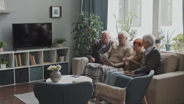 白人高齢者のグループは デジタルタブレットを使用し 老人ホームでソファに座って話をする — ストック動画