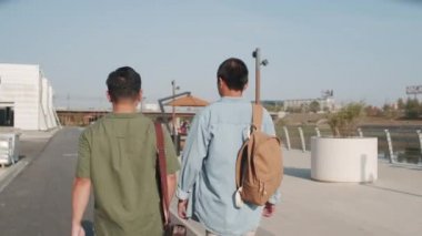 Gündelik giyimli iki Asyalı gencin yaz aylarında set boyunca açık havada yürürken çekilmiş bir fotoğrafı.