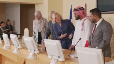 Farklı ülkelerden beş çok ırklı erkek ve kadın politikacının basın konferansında kameralara poz verirken orta boy çekimleri.