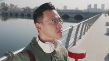 Gözlüklü genç Asyalı adamın portresini yakından çek. Kahvesini iç ve güneşli bir günde nehir kenarına bak.