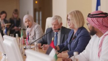 Kafkas kökenli orta yaşlı kadın politikacının basın toplantısında mikrofonla çeşitli ülkelerden dört siyasi liderle oturduğu orta boy bir fotoğraf.