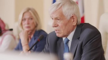 Resmi basın toplantısı sırasında mikrofondan konuşan üst düzey Kafkas erkek politikacının orta ölçekli görüntüsü