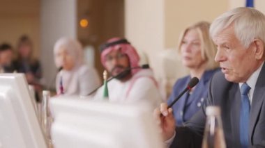 Basın toplantısı sırasında mikrofonla konuşan, farklı ülkelerden siyasi liderlerle masaya oturan olgun Kafkas politikacılarının belini bükmek.