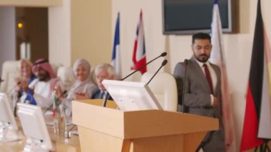 Orta Doğu ülkesinin ciddi siyasi liderinin konferans salonunda tribün başında durup farklı ülkelerden siyasetçilere ve izleyicilere konuşmasını yaparken orta ölçekli bir fotoğrafı.