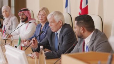 Olgun beyaz politikacının basın toplantısında konuşmasını bitirdiği orta boy bir fotoğraf. Seyirciler ve diğer ülkelerin temsilcileri onu alkışlıyor.