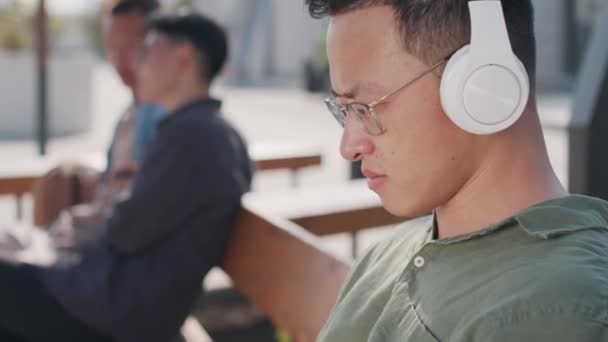 Tilt Close Young Asian Man White Wireless Headphones Eyeglasses Typing — Vídeo de Stock
