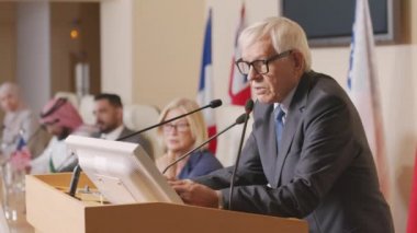 Resmi basın toplantısı sırasında Tribün 'de konuşma yaparken notlarına bakan olgun Kafkas siyasi liderinin orta boy fotoğrafı.