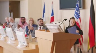 Çok ırklı siyasi liderlerle birlikte basın konferansına gelen küçük bir çevreci aktivistin orta ölçekli görüntüsü konuşma yapmak için Tribün 'e gidiyor.