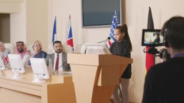 Çevre topluluğunun çıkarlarını temsil eden küçük bir kızın konuşma yaptığı orta boy bir fotoğraf ve konferans salonunda tribünde duran siyasi liderler kameranın önünde konuşma yapıyor.