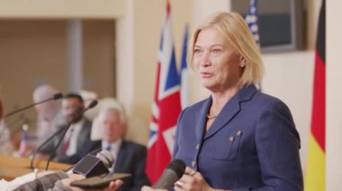 Beyaz ırkın orta yaşlı kadın siyasi liderinin konferansta basına verdiği röportajın orta fotoğrafı.