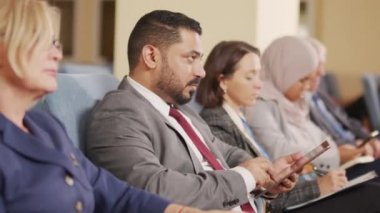 Orta Doğulu erkek politikacının konferans salonundaki siyasi konferans konuşmasını dinlerken dijital tablete notlar alırken PAN çekimi