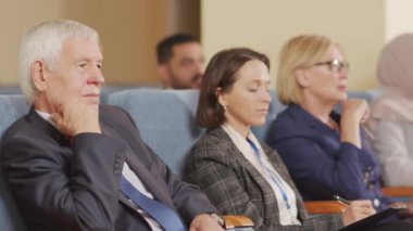 Konferans salonunda oturup konferans dinleyen ve notlar alan başarılı iş adamları ve kadınların PAN çekimi