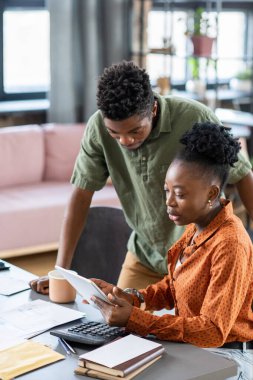 Genç Afrikalı bir adam tabletle kadın meslektaşının üzerine eğiliyor.
